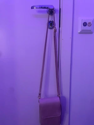 Ljusrosa axelväska med dragkedjor - Säljer en ljusrosa axelväska med lång justerbar rem och flera fack med dragkedja. Väskan har en stilren, rektangulär form och stängs med tryckknapp. Perfekt för att organisera dina grejer och hålla koll på allt. Har använt den ett par gånger men har slitits på ena sidan innanför dragkedjan (syns på bild 4). Men det är inget som merks av eller syns utanpå. Men annars är den som ny. Pris kan diskuteras.💓