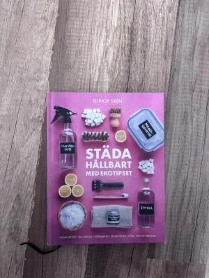 Städa hållbart med Ekotipset - Boken 'Städa hållbart med Ekotipset' av Ellinor Sirén är en guide till miljövänlig städning. Omslaget är rosa med bilder på naturliga rengöringsmedel, borstar och citroner. Perfekt för dig som vill ha smarta eko-hacks och tips för ett grönare hem.