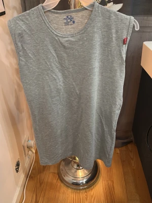 Ljusgrå ärmlös linnetopp - En enkel och stilren ljusgrå linnetopp från Cotonil. Toppen är ärmlös med rund halsringning och har en mjuk, bekväm känsla i bomullsmaterial. Perfekt för en avslappnad look.