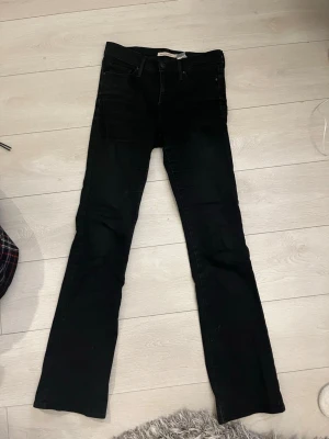 Svarta bootcut jeans från Levis - Säljer ett par svarta Levis jeans med bootcut passform. Klassisk femficksmodell med normal midja och raka ben som släpper ut lite vid ankeln. Jeansen är i ett mjukt och stretchigt bomullsmaterial, perfekta till vardagslooken.