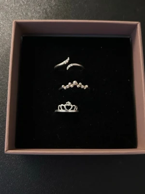 Söta silverfärgade ringar med stenar - Ett ring sett med 3 ljus silvriga ringar i, två för övriga fingrar och en tiara formad gjord för lillfingret. Storlek 17 för de övre och ca storlek ~15 för den mindre!