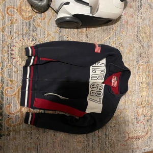 Marinblå hoodie med amerikanska flaggan - Tröja med amerikanska flaggan på ärmen säljes för en spottstyver. 