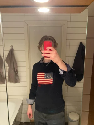Mörkblå stickad tröja Polo Ralph Lauren - Polo Ralph Lauren USA tröja i närmast perfekt skick! Snygg över en skjorta eller bara som sig själv, Personen på bilden är 180 cm och väger 65kg. Storleken är XL i barn men passar M, Hör av er om funderingar!