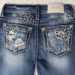 Miss Me Jeans Bootcut – Strl 23 | Broderade fickor | Y2K - Stilrena och ikoniska Miss Me-jeans i klassisk bootcut-modell. Kända för sina detaljer – här med broderade bakfickor, stenar och slitningar som ger den där eftertraktade Y2K / early 2000s-looken.  Perfekta till boots eller klackar. Tajta över höft & lår med utsvängda ben nertill.  📏 Storlek & passform 	•	Märkt storlek: 23 	•	Passform: Bootcut / flare 	•	Midja (rakt över): ca 37 cm 	•	Innerbenslängd: ca 74,5 cm 	•	Ytterlängd: ca 96 cm