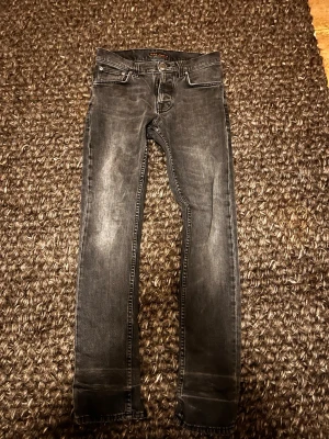 Nudie jeans - Snygga svarta Nudie jeans i modellen Grim Tim i storleken 38:32. Dem är slim fit. Det är lagning i grenen och ett hål längst ner på benet.