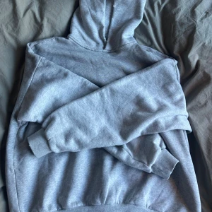 Grå hoodie från Acne Studios - Säljer en grå hoodie från Acne Studios med tryck på ryggen där det står 'Acne Studios STOCKHOLM 1996'. Klassisk modell med huva och ribbade muddar. Mjuk insida och avslappnad passform, perfekt för chill dagar. Tveka inte på att höra av er!!!