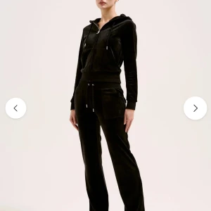 Svart juicy couture  - Svart hoodie i mjuk velour med huva och dragsko. Tröjan har hel dragkedja framtill, ribbade muddar och fickor på magen. Perfekt för chill dagar eller när du vill vara extra comfy.