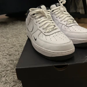 Nike Air Force 1 strl 44 - Säljer ett par Nike Air Force 1 '07 LV8 i vitt och svart. Klassisk low-top sneaker i skinn med perforerad tå, svart häl och detaljer, samt svart sula. Ikonisk Swoosh på sidorna och snörning framtill. Perfekt för dig som gillar stilrena och tidlösa sneakers. Använda ca 3 gånger. Skriv för mer information. Pris kan alltid diskuteras! 