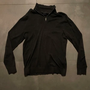 Grå half zip tröja Jack & Jones - Grå långärmad tröja från Jack & Jones med half zip-dragkedja i halsen. Tröjan är i mjukt stickat material och har en klassisk, stilren look som passar perfekt till lager-på-lager. Enkel att matcha med både jeans och chinos. Storlek M