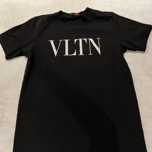 Svart t-shirt från Valentino - Svart t-shirt från Valentino med stor vit VLTN-logga på bröstet. Klassisk rund halsringning och korta ärmar. Her en riktigt clean look och passar bra  för dig som gillar stilrena designer och exklusiva märken. Hör gärna av dig vid frågor!