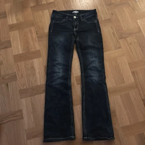 Bootcut jeans från Gina Tricot, stl 164 - Mörkblå bootcut jeans från Gina Tricot med snygga kontrastsömmar och broderade detaljer med paljetter på bakfickorna. Klassisk femficksmodell i jeansmaterial, perfekt för dig som gillar en lite vidare passform nertill.