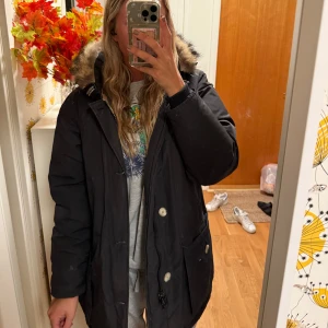Woolrich jacka - Svart woolrich jacka med päls luva. Har små vita fläckar som säkert går bort i tvätten. Annars är den hel och fin!