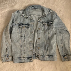 Ljusblå jeansjacka från Vero Moda XS - Snygg ljusblå jeansjacka från Vero Moda i klassisk modell med knappar framtill och två bröstfickor med lock. Jackan har långa ärmar och coola sömdetaljer. Perfekt för dig som gillar en avslappnad och trendig stil.