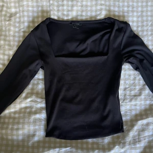 Svart långärmad topp från New Yorker  - Säljer en svart långärmad topp från New Yorker med fyrkantig ringning. Toppen är figurnära och har en stilren, minimalistisk look. Perfekt att styla med jeans eller kjol för en clean vibe.