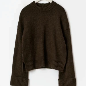 Brun stickad tröja Gina - Mysig mörkbrun stickad tröja med rund hals och breda ribbade muddar vid ärmslut och nederkant. Tröjan har en loose, oversized passform och långa ärmar som ger en chill vibe. Perfekt att slänga på sig när det är kallt ute.