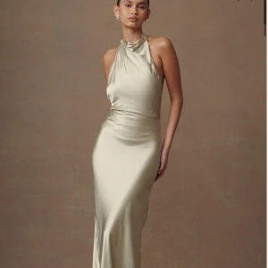 Grön långklänning i satin - Supersnygg långklänning i en grön färg i satin med halterneck och öppen rygg. Klänningen har en elegant, figurnära passform och knappar längs ryggen. Perfekt för dig som vill sticka ut med en stilren och lyxig look. Säljer då den tyvärr är för kort för mig!!😭(hade tänkt ha som balklänning). Skulle säga att den passar någon som är 163cm och under (med klackar!!)