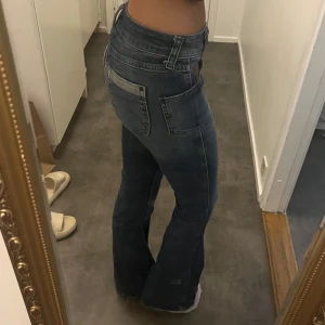 Blå bootcut jeans från BDG Urban Outfitters - Snygga blå jeans från BDG Urban Outfitters med bootcut-modell och midwaist. Jeansen har klassiska fickor med coola kontrastsömmar och detaljer på bakfickorna. Tillverkade i jeansmaterial som ger en skön passform och stilren look.