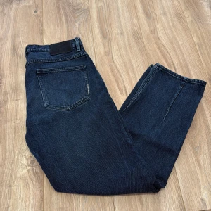 Mörkblå jeans från Neuw (Studio Relaxed) - Snygga mörkblå jeans från Neuw med klassisk femficksdesign och svart patch bak i midjan. Jeansen har raka ben och är tillverkade i robust denim med tydliga sömmar. Perfekta för dig som gillar stilrena och tidlösa jeans. 