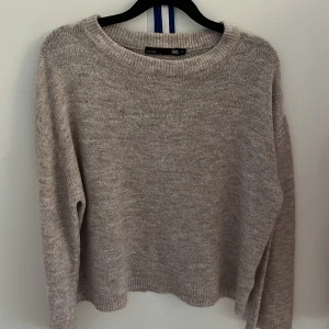 Beige stickad tröja från 157 XS - Mysig beige stickad tröja från 157 i storlek XS. Tröjan har rund halsringning, ribbade muddar och lång ärm. Perfekt för lager-på-lager och chill dagar. Enkel och stilren design som passar till allt.
