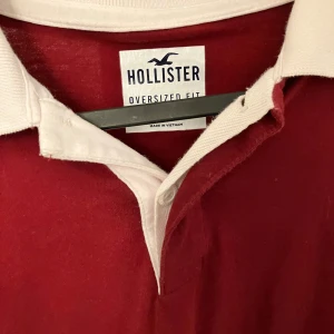 Vinröd oversized pikétröja från Hollister - Säljer en vinröd långärmad pikétröja från Hollister i oversized fit. Tröjan har vit krage och knäppning framtill, samt en snygg Hollister-logga på ärmen. Perfekt för dig som gillar en avslappnad och sportig stil.OBS mörkare än på bilderna, tröjan är vinröd inte röd. 
