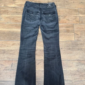 True Religion svarta bootcut jeans - Svarta jeans från True Religion i modellen Becca Mid Rise Bootcut. Tillverkade i mjukt denimtyg som sitter skönt och ger en cool look. Del ör i gott skick och har inga tecken på skador. Dem är i storlek 23. Jag köpte dem för 1400 kr på Kenja så jag säljer dem för halva priset = 700