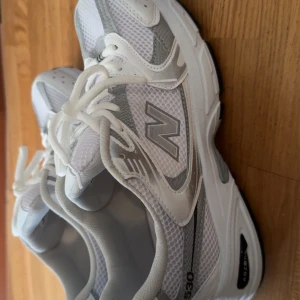 New Balance 530 vita sneakers - Snygga New Balance 530 sneakers i vitt och silver med mesh och syntetmaterial. Skorna har klassisk snörning, rund tå och en chunky sula med svarta detaljer undertill. Perfekta för dig som gillar sportig och trendig stil.