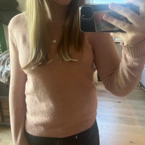 Rosa stickad tröja från Vila - Mysig rosa stickad tröja från Vila med rund halsringning och ribbade muddar vid ärmslut och nederkant. Perfekt för lager-på-lager och enkel att matcha med jeans eller kjol. Långärmad och i en mjuk, skön kvalitet.