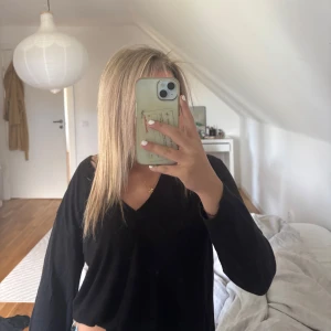 Svart v-ringad stickad tröja - En svart stickad tröja med v-ringning och långa ärmar. Tröjan har en enkel och clean design, perfekt att styla med jeans eller kjol. Mjuk och skön känsla, passar dig som gillar en klassisk look.