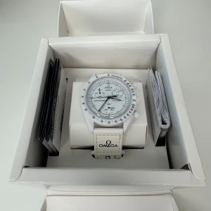 Omega x Swatch – Mission to the Moonphase (Full Moon) - Omega x Swatch – Mission to the Moonphase (Full Moon) 	•	Vit modell, släppt 2024. 	•	Nyskick, inga repor eller märken. 	•	Originalarmband och urverk i perfekt skick. 	•	Aldrig använd utanför hemmet. 	•	Säljes komplett.                                                   Hör av dig vid frågor eller funderingar!