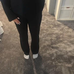 Svarta raka kostymbyxor - Snygga svarta kostymbyxor med rak passform och låg midja. Byxorna har klassisk look och är perfekta för en stilren outfit. Materialet känns mjukt och följsamt, vilket gör dem bekväma att bära hela dagen.