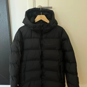 Svart dunjacka från J.Lindeberg - Säljer en svart dunjacka från J.Lindeberg som är använd sparsamt. Inga skador eller defekter, ser ut som ny. Storlek M 