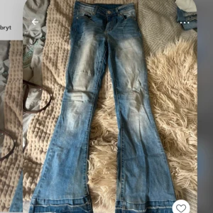 Blå bootcut jeans - Snygga blå jeans med bootcut-modell och ljusa slitningar framtill. Jeansen har en cool, utsvängd passform och är tillverkade i mjukt denimtyg.