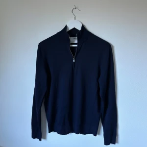 Mörkblå half zip-tröja Selected Homme - Mörkblå långärmad tröja från Selected Homme med half zip-dragkedja i halsen. Tröjan har en stilren och enkel design med ribbade muddar och hög krage. Perfekt för lager-på-lager och passar till många olika outfits. 3Y17