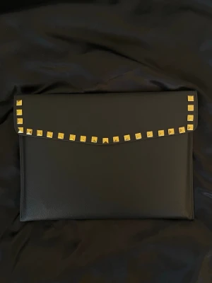 Datorfodral med guldnitar i läder imitation  - LEVERANS 2-5 arbetsdagar 💕Rea - endast 199 kr (ord. pris 249 kr)! Stilrent datorfodral tillverkat av veganskt läder i vattentätt material. Fodralet stängs med knapp. Fodralet skyddar din dator effektivt samtidigt som det ger din outfit en extra touch. ⚜️ Storlek: 34 × 25 cm – passar svarta HP Chromebooks och andra datorer i liknande storlek. 