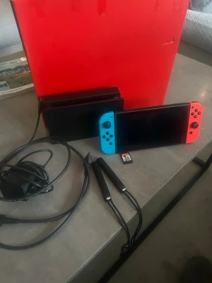 Nintendo Switch med neonröda och blå Joy-Cons - Nintendo switch från år 2022 Version 2 med bättre batteri! Skärmen är i mycket fint skick Super Mario Bros wonder ingår. 2 joy cons.  