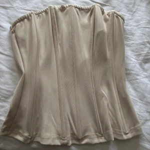 Beige korsett - Säljer en snygg beige korsett ish tubtopp med dragkedja i ryggen, jätte fin💓väldigt stretchigt material💛använd 1 gång
