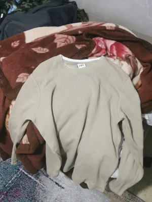 Beige sweatshirt från ZARA - Snygg beige sweatshirt från ZARA i storlek L. Tröjan har rund halsringning och är tillverkad i ett mjukt, ribbat material. Enkel och stilren design som passar perfekt till jeans eller joggers.
