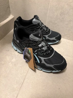 Svarta Asics sneakers med grå detaljer - Snygga svarta Asics sneakers med grå och ljusblå detaljer. Skorna har meshpaneler för bra ventilation, snörning och en bekväm GEL-sula. Perfekta för dig som gillar sportig stil och vill ha riktigt sköna sneakers till vardags. Storlek 46 men passar även mig som har storlek 43.