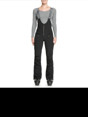 Svarta skidbyxor med hängslen Roxy - Säljer ett par svarta skidbyxor från Roxy med justerbara hängslen och dragkedja framtill. Byxorna har flera fickor med dragkedja och är tillverkade i ett slitstarkt, vattenavvisande material. Perfekta för skidåkning eller andra vinteraktiviteter.