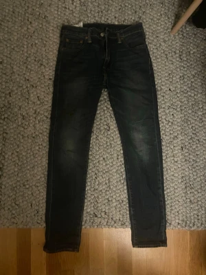 Levi's 510 mörkblå jeans - Säljer ett par Levi's 510 jeans i mörkblå tvätt. Klassisk femficksmodell med smal passform och raka ben. Jeansen har snygga slitningar och är tillverkade i tåligt denimtyg. Perfekta för dig som gillar en clean och tidlös look.