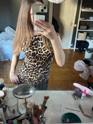 Leopardmönstrad ärmlös topp - Säljer en snygg ärmlös topp med leopardmönster. Toppen har en tight passform och är perfekt för dig som vill sticka ut. Materialet känns mjukt och stretchigt, troligen polyester. Passar till dig som gillar djurmönstrat och vill ha en trendig look.