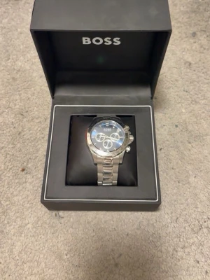 Hugo Boss Hero klocka blå/silver - Snygg herrklocka från Hugo Boss, modell Hero. Klockan har en blå urtavla med flera små urtavlor och datumvisning, boett i rostfritt stål och grå länk. Diameter 45 mm, stilren och modern design som sticker ut. Pris 1500kr fast vid snabb affär kan priset diskuteras.