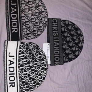 Christian Dior mössa  - Säljer en snygg stickad mössa från Christian Dior med tydligt logomönster och texten J'ADIOR eller CHRISTIAN DIOR framtill. Finns i svartvitt och grått, perfekt för dig som vill ha en trendig accessoar med lyxig känsla. Materialet är mjukt och stretchigt för skön passform. Ett tusen för mössan i toppen då den är bättre och snyggare