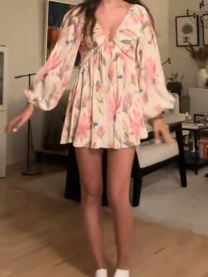 Blommig kortklänning med v-ringning - Supersöt kortklänning med blommigt mönster i ljusa toner av rosa, beige och grönt. Klänningen har djup v-ringning, långa puffärmar och flowy passform. Perfekt för sommarens alla tillfällen och ger en romantisk vibe. Är i nyskick då jag inte använt den mer än 2 gånger. M men passar S med!