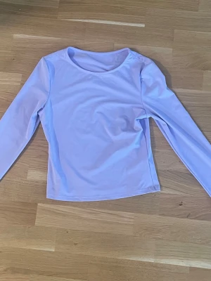 Ljuslila långärmad topp - En stilren ljuslila långärmad topp med rund halsringning. Tillverkad i ett mjukt och stretchigt material som sitter bekvämt på kroppen. Perfekt att matcha med jeans eller kjol för en enkel och fräsch look.