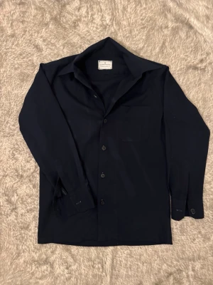 Skjorta  - Strykfri marinblå skjorta i storlek M men passar S/M. Skjortan tillverkad i mjuk bomull och har en clean, tidlös look med normal passform och enkel krage. Kontakta gärna om ni har några frågor eller funderingar gällande pris eller plagg. 