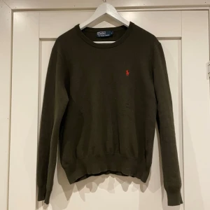 Mörkgrön merino ull tröja från Polo Ralph Lauren - Klassisk mörkgrön tröja från Polo Ralph Lauren i mjuk ull. Tröjan har rund halsringning, långa ärmar och den ikoniska röda loggan broderad på bröstet. Perfekt till höst och vinter för en stilren look. Tröjan va i storlek L men sitter mer som en S nu