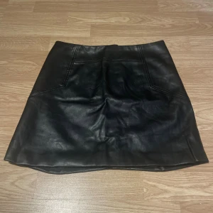 Svart kjol i skinn H&M - Säljer en svart kort kjol från H&M i skinn, storlek 36. Dragkedja bak. 