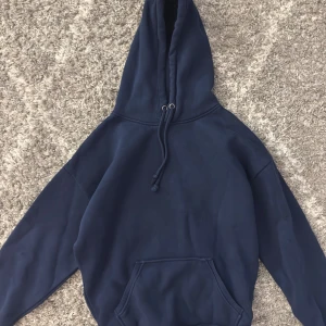 Mörkblå hoodie med huva - Säljer en stilren mörkblå hoodie från bikbok som inte säljs längre. Perfekt för dig som gillar en avslappnad och bekväm stil. Använd endast ett fåtal gånger😊