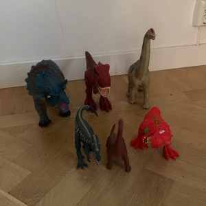 Dinosaurer  - Bilden visar sex olika dinosaurieleksaker i plast, i varierande färger och former. De är detaljerade och passar perfekt för barn som gillar dinosaurier. Leksakerna verkar vara i gott skick utan synliga skador eller större slitage.